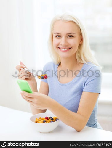 healthy eating, dieting and people concept - smiling young woman with tablet pc computer eating breakfast with smartphone at home