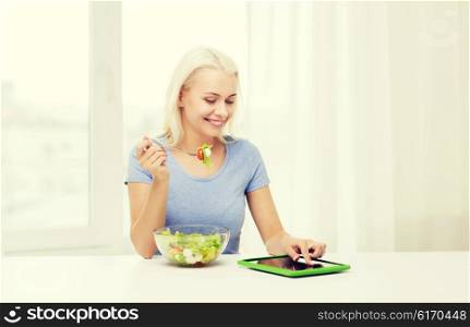 healthy eating, dieting and people concept - smiling young woman with tablet pc computer eating vegetable salad at home