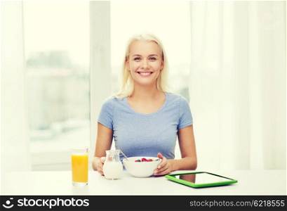 healthy eating, dieting and people concept - smiling young woman with tablet pc computer eating breakfast at home