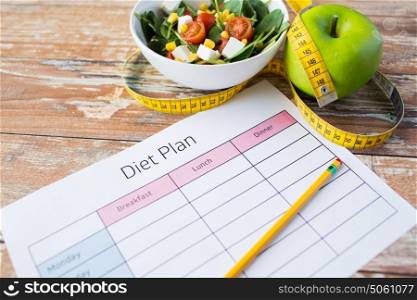 healthy eating, dieting, slimming and weigh loss concept - close up of diet plan paper with green apple, measuring tape and salad. close up of diet plan and food on table