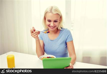 healthy eating, dieting, technology and people concept - smiling young woman with tablet pc computer eating breakfast at home