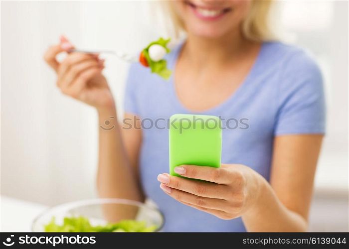 healthy eating, dieting, technology, food and people concept - close up of smiling young woman with smartphone eating vegetable salad at home