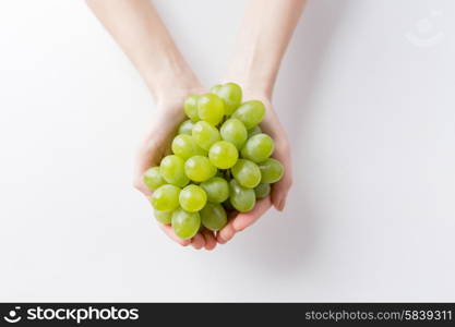 healthy eating, dieting, vegetarian food and people concept - close up of woman hands holding green grape bunch at home