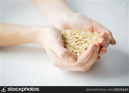 healthy eating, dieting, vegetarian food and people concept - close up of woman hands holding oatmeal flakes at home