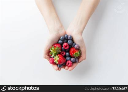 healthy eating, dieting, vegetarian food and people concept - close up of woman hands holding berries at home