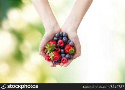 healthy eating, dieting, vegetarian food and people concept - close up of woman hands holding different ripe summer berries over green natural background