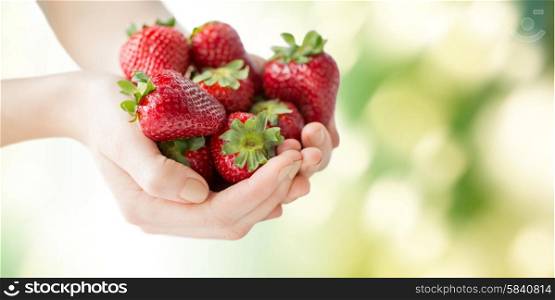 healthy eating, dieting, vegetarian food and people concept - close up of woman hands holding ripe strawberries over green natural background