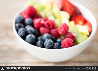 healthy eating, dieting, vegetarian food and people concept - close up of fruits and berries in bowl on table
