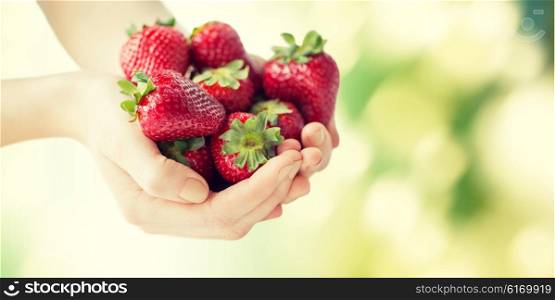 healthy eating, dieting, vegetarian food and people concept - close up of woman hands holding ripe strawberries over green natural background