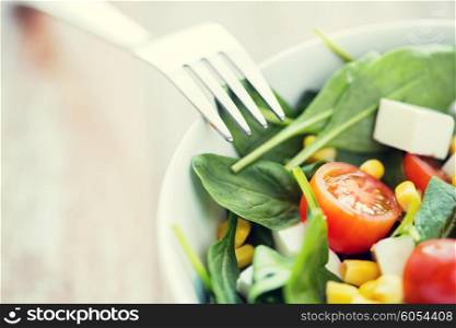 healthy eating, dieting, vegetarian kitchen and cooking concept - close up of vegetable salad bowl and fork at home