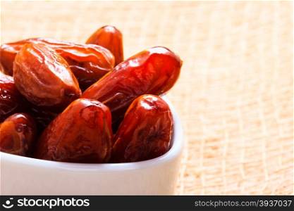Healthy eating. Dried dates in white bowl on table cloth rustic background
