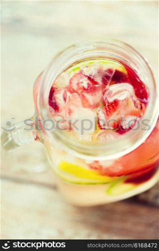 healthy eating, drinks, diet and detox concept - close up of fruit water with lime, lemon and cucumber in glass bottle