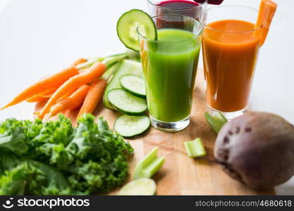 healthy eating, drinks, diet and detox concept - close up of glasses with different fruit or vegetable juices and food on table