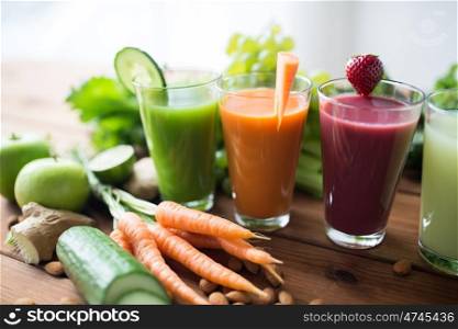 healthy eating, drinks, diet and detox concept - close up of glasses with different fruit or vegetable juices and food on table