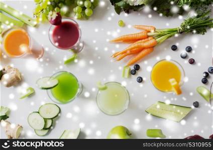 healthy eating, drinks, diet and detox concept - close up of glasses with different fruit or vegetable juices and food on table over snow. glasses with different fruit or vegetable juices
