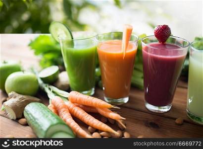 healthy eating, drinks, diet and detox concept - close up of glasses with different fruit or vegetable juices and food on table over green natural background. glasses with different fruit or vegetable juices. glasses with different fruit or vegetable juices