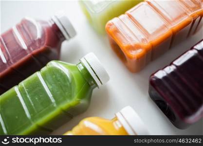 healthy eating, drinks, diet and detox concept - close up of plastic bottles with different fruit or vegetable juices on white