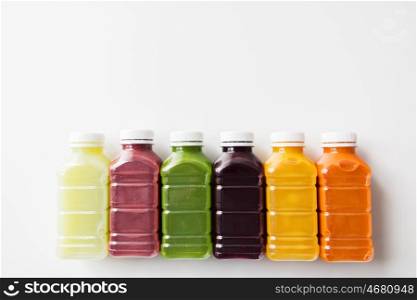 healthy eating, drinks, diet and detox concept - close up of plastic bottles with different fruit or vegetable juices on white