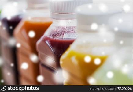 healthy eating, drinks, diet and detox concept - close up of plastic bottles with different fruit or vegetable juices over snow. bottles with different fruit or vegetable juices