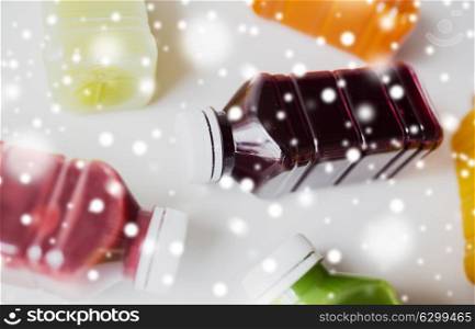 healthy eating, drinks, diet and detox concept - close up of plastic bottles with different fruit or vegetable juices on white over snow. bottles of different fruit or vegetable juices