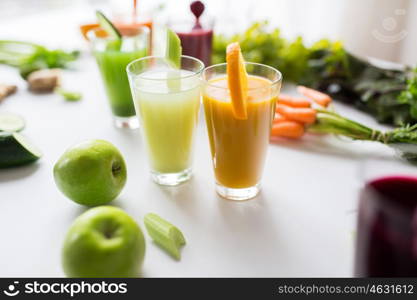 healthy eating, drinks, diet and detox concept - glasses with different fruit or vegetable juices and food on table