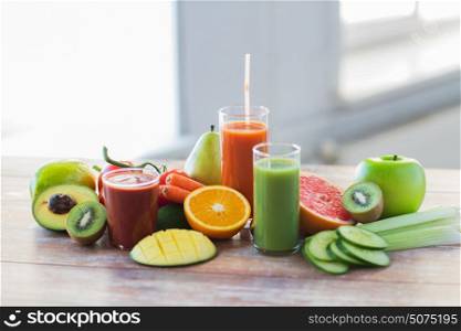 healthy eating, drinks, diet and detox concept - glasses with different fruit or vegetable juices and food on table. glasses with different fruit or vegetable juices