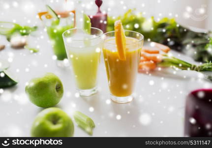 healthy eating, drinks, diet and detox concept - glasses with different fruit or vegetable juices and food on table over snow. glasses with different fruit or vegetable juices