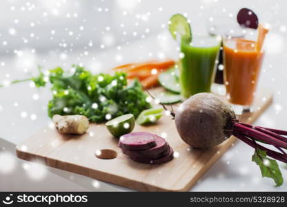 healthy eating, drinks, diet and detox concept - glasses with vegetable fresh juices and food on table over snow. glasses with different vegetable fresh juices