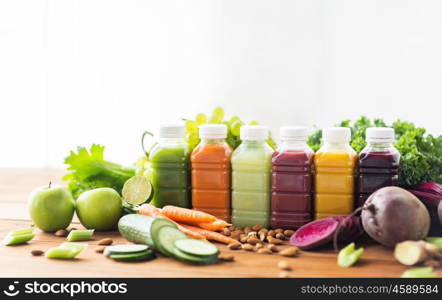 healthy eating, drinks, diet and detox concept - plastic bottles with different fruit or vegetable juices and food on wooden table