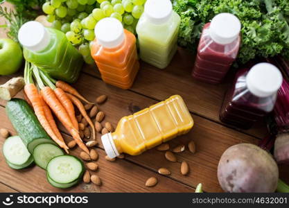 healthy eating, drinks, diet and detox concept - plastic bottles with different fruit or vegetable juices and food on wooden table