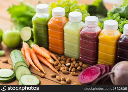 healthy eating, drinks, diet and detox concept - plastic bottles with different fruit or vegetable juices and food on wooden table