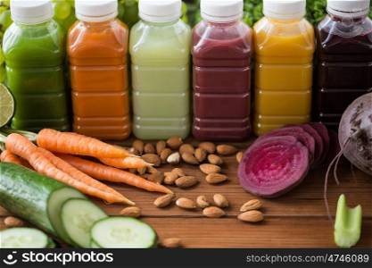 healthy eating, drinks, diet and detox concept - plastic bottles with different fruit or vegetable juices and food on wooden table