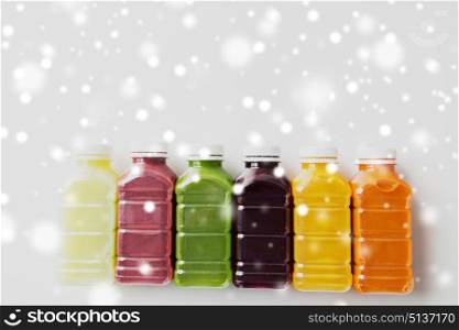 healthy eating, drinks, diet and detox concept - plastic bottles with different fruit or vegetable juices on white over snow. bottles with different fruit or vegetable juices