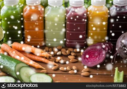 healthy eating, drinks, diet and detox concept - plastic bottles with different fruit or vegetable juices and food on wooden table over snow. bottles with different fruit or vegetable juices