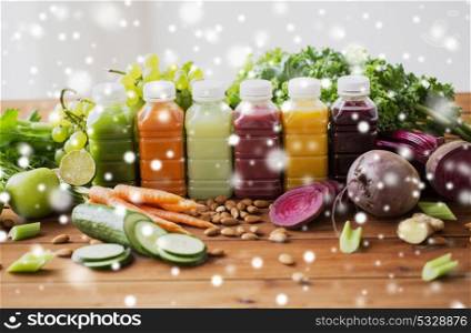 healthy eating, drinks, diet and detox concept - plastic bottles with different fruit or vegetable juices and food on wooden table over snow. bottles with different fruit or vegetable juices