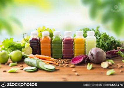 healthy eating, drinks, diet and detox concept - plastic bottles with different fruit or vegetable juices and food on wooden table over green natural background. bottles with different fruit or vegetable juices. bottles with different fruit or vegetable juices