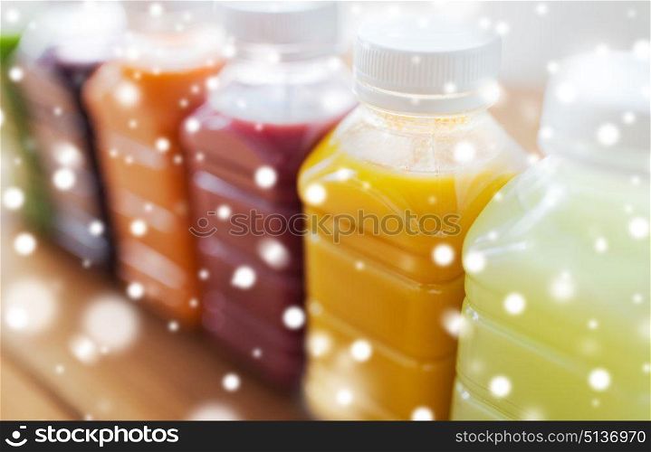 healthy eating, drinks, diet and packaging concept - plastic bottles with different fruit or vegetable juices on wooden table over snow. bottles with different fruit or vegetable juices