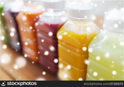 healthy eating, drinks, diet and packaging concept - plastic bottles with different fruit or vegetable juices on wooden table over snow. bottles with different fruit or vegetable juices