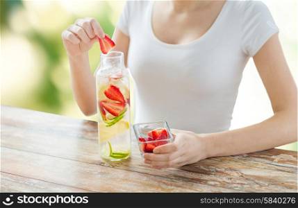 healthy eating, drinks, diet, detox and people concept - close up of woman with fruit water in glass bottle over green natural background