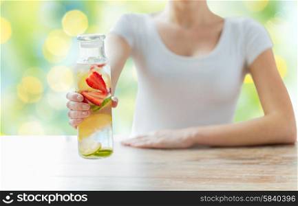 healthy eating, drinks, diet, detox and people concept - close up of woman with fruit water in glass bottle over green lights background