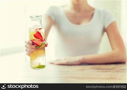 healthy eating, drinks, diet, detox and people concept - close up of woman with fruit water in glass bottle