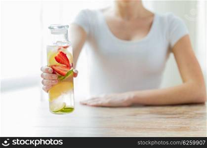 healthy eating, drinks, diet, detox and people concept - close up of woman with fruit water in glass bottle