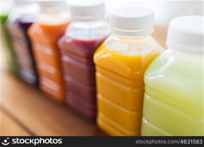 healthy eating, drinks, dieting and packaging concept - close up of plastic bottles with different fruit or vegetable juices on wooden table