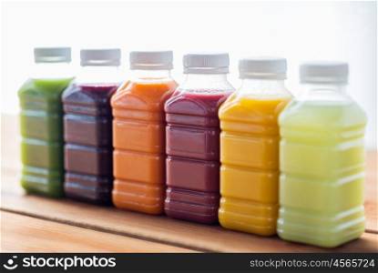 healthy eating, drinks, dieting and packaging concept - plastic bottles with different fruit or vegetable juices on wooden table