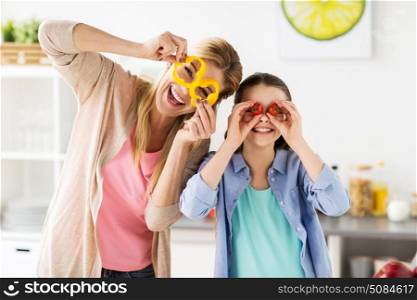 healthy eating, family and people concept - happy mother and daughter cooking vegetables and having fun at home kitchen. happy family cooking and having fun at kitchen. happy family cooking and having fun at kitchen