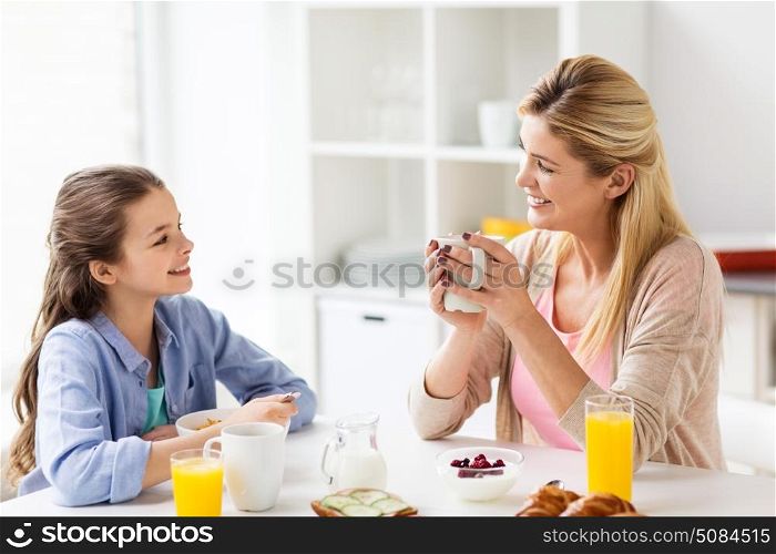 healthy eating, family and people concept - happy mother and daughter having breakfast at home kitchen. happy family having breakfast at home kitchen. happy family having breakfast at home kitchen