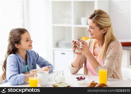 healthy eating, family and people concept - happy mother and daughter having breakfast at home kitchen. happy family having breakfast at home kitchen. happy family having breakfast at home kitchen