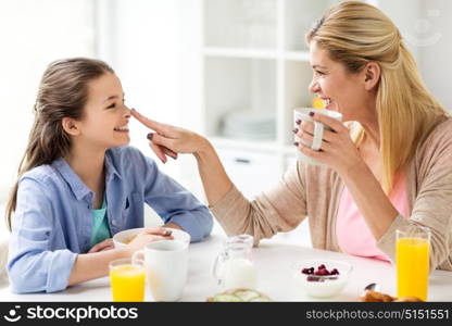 healthy eating, family and people concept - happy mother and daughter having breakfast at home kitchen. happy family having breakfast at home kitchen