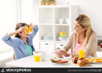 healthy eating, family and people concept - happy mother and daughter having breakfast at home kitchen. happy family having breakfast at home kitchen