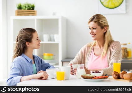 healthy eating, family and people concept - happy mother and daughter having breakfast at home kitchen. happy family having breakfast at home kitchen